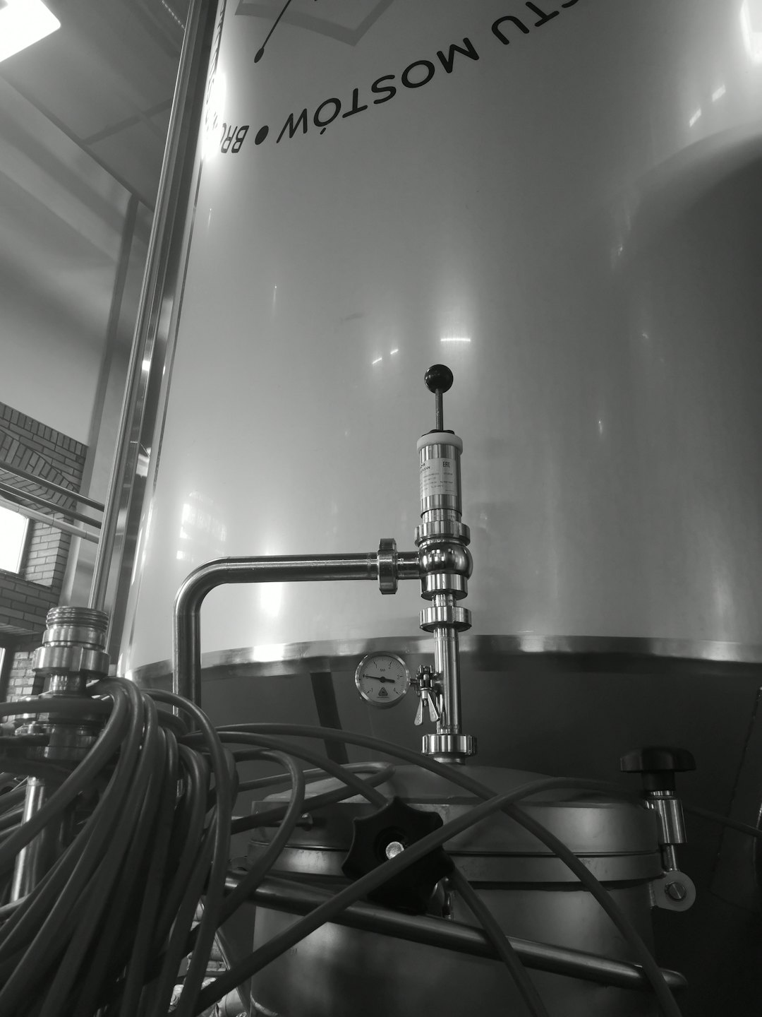 Tanques de fermentación industrial brillantes con tuberías dentro de una planta de producción.